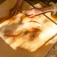 two people are making something out of paper on the ground with their hands over it