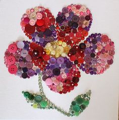 a flower made out of buttons on a white background with a chain attached to it