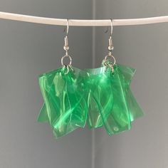 green glass earrings hanging from a clothes line