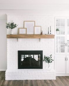 a white brick fireplace with wood mantle and framed pictures on it's shelf above the fire place