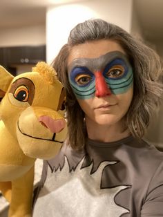 a woman with her face painted like a lion and a stuffed animal in front of her