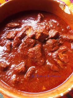 a bowl filled with meat and sauce on top of a table