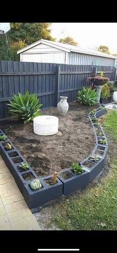 a garden with various plants and rocks in the middle, along side a fenced yard