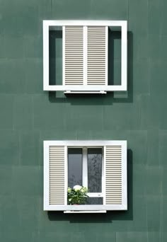 two windows on the side of a green building with white shutters and flower box