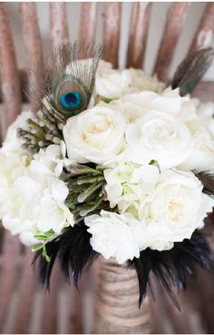 a bridal bouquet with white flowers and peacock feathers