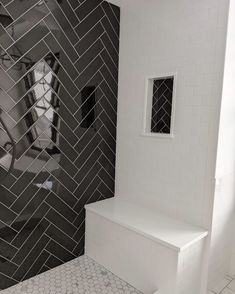 a white toilet sitting next to a black and white tiled shower stall in a bathroom