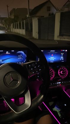 the interior of a car with purple lights on it and dashboard controls in front of him