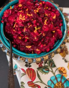 a blue bowl filled with cranberry sauce on top of a floral table cloth