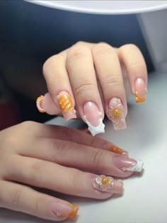 a woman's hands with french manies and yellow flowers on them, holding onto a white table