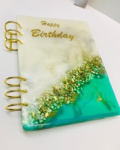 a spiral notebook with the words happy birthday written in gold and green on top of it