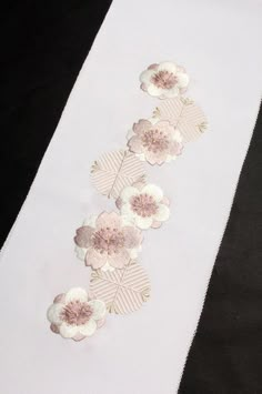 white table runner with pink flowers and leaves on black background, ready to be used as decoration