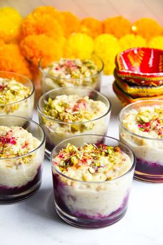 there are many desserts in small glass cups on the table with flowers around them