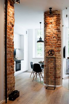 an open living room and dining area with brick walls, wood flooring and chairs