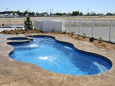 an empty swimming pool in the middle of a yard with white fence and gate around it