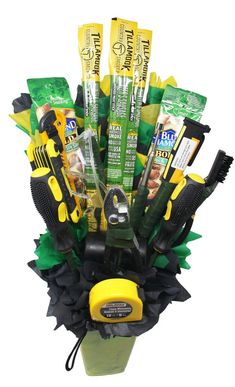 a bunch of tools are in a bucket with green leaves on the bottom and yellow handles