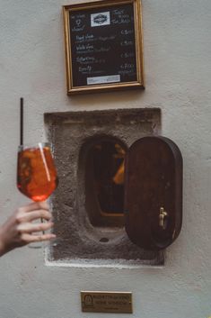 a person holding a wine glass in front of a wall