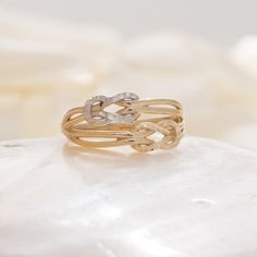 a gold ring sitting on top of a white marble slab with an intricate knot in the middle