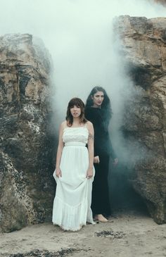 two women standing next to each other in front of steam rising up from the ground