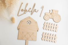 wooden cutouts with farm animals, tractor and fence on white surface next to feathers