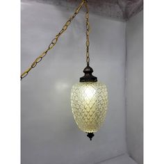 a glass light hanging from a chain in a room with white walls and flooring