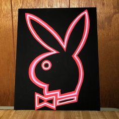 a neon rabbit head with a bow tie on it's head is shown in front of a wooden wall