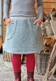 a woman wearing red tights and boots standing in front of a pile of wood