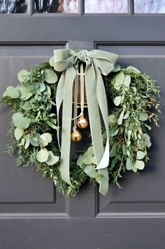 a christmas wreath with bells and greenery on the front door