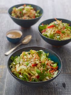 three bowls filled with salad on top of a wooden table