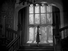 a woman walking up the stairs in front of a window