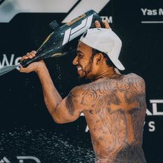 a tattooed man holding a tennis racquet over his head while standing in the rain