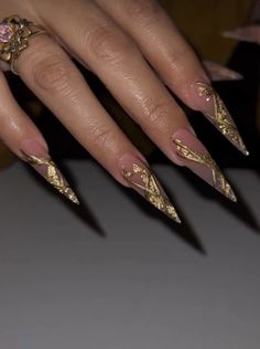 a woman's manicured nails with gold leaf designs on the tip of them