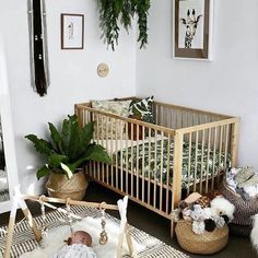 a baby is laying in a crib next to some plants and other things on the floor