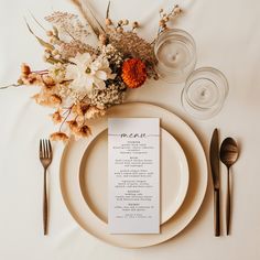 a table setting with place settings, silverware and an arrangement of flowers on it