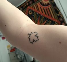 a person with a tattoo on their arm that has a maple leaf in the middle