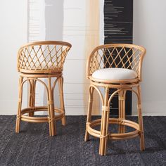 two wicker bar stools in front of a wall with a painting on it