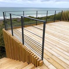 a wooden deck next to the ocean with metal railings