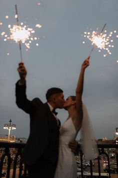 a newly married couple kissing while holding sparklers