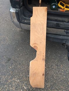 a wooden object laying on the ground next to a car