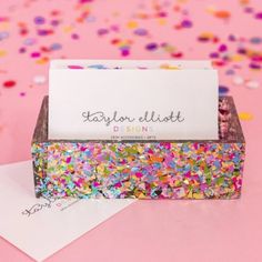 a business card holder with confetti sprinkles on it and a pink background