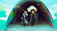 two young boys are walking out of a tunnel