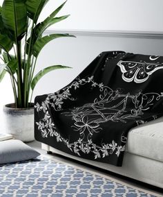 a black and white blanket on a couch next to a potted plant