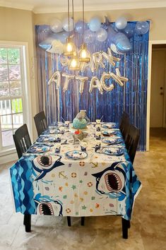 a dining room table is decorated with blue and white balloons, shark decorations, and an under - the - sea theme