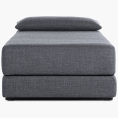 a grey couch with two pillows on it and one pillow is folded over the top