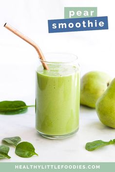 pear smoothie in a glass with a straw and green leaves on the table next to it