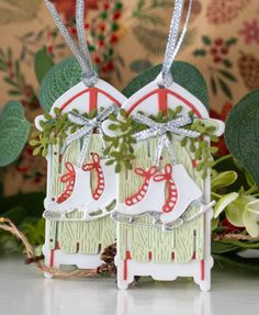 two small christmas houses with bows and ribbons hanging from the front, on top of a table