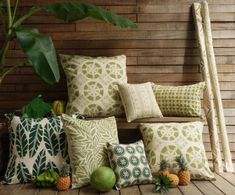 a bunch of pillows sitting on top of a wooden floor next to a plant and some fruit