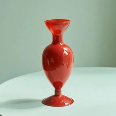 a red vase sitting on top of a white table