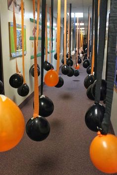 an image of balloons hanging from the ceiling in a hallway with orange and black streamers