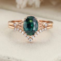 a ring with an oval green stone surrounded by white and rose gold diamonds on top