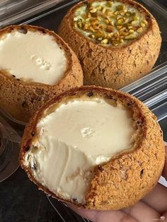 three baked desserts in plastic containers with toppings on them, one being filled with ice cream and the other containing pistachio